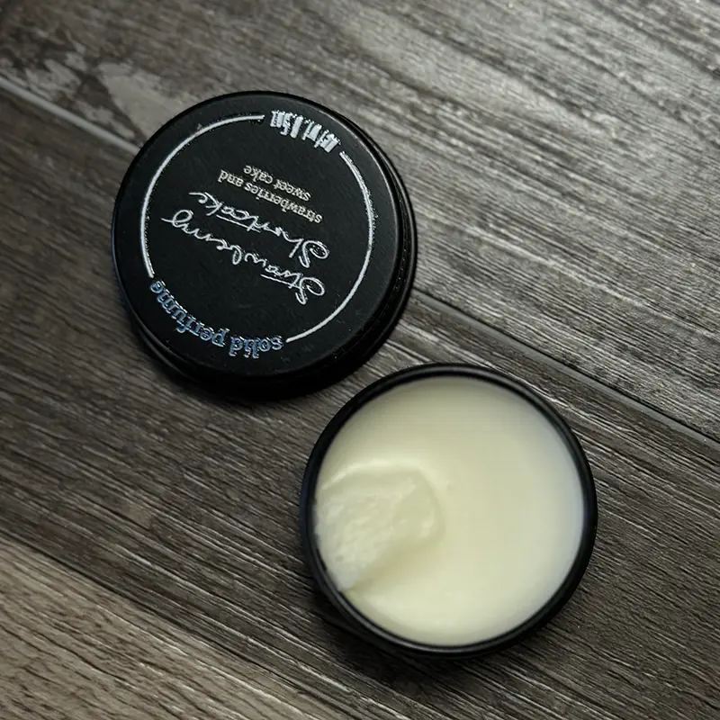 an open tin of solid perfume arranged against a faux wood background