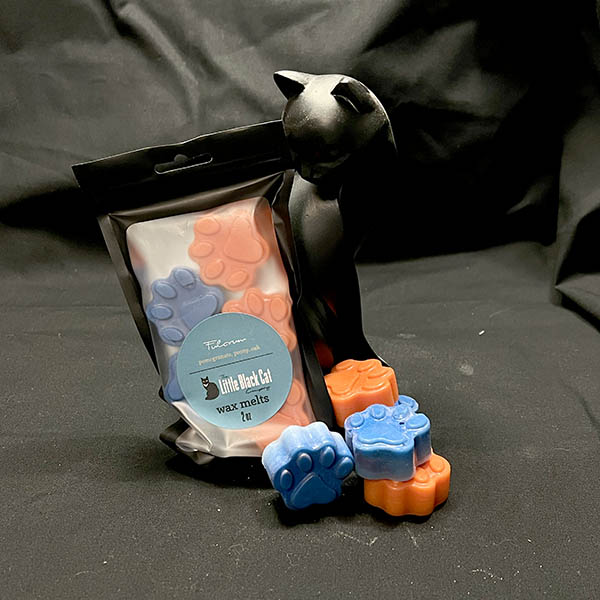 wax melts piled artfully in front of an art deco cat statue