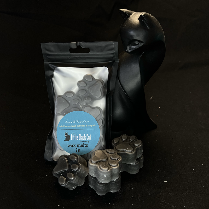 gray paw print shaped wax melts piled artfully in front of an art deco cat statue