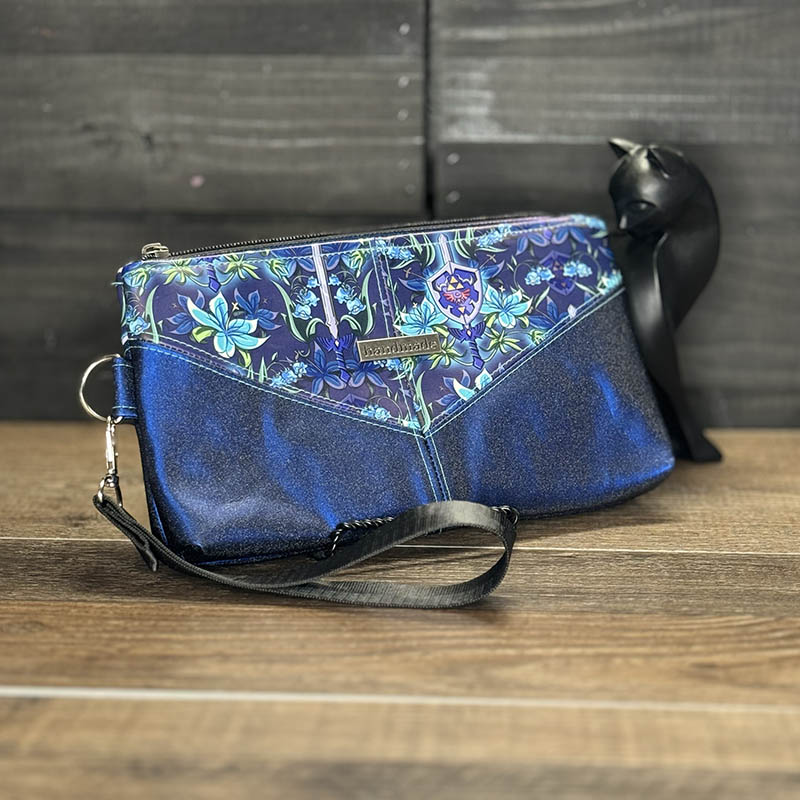 handmade wristlet featuring a floral shield and sword design with glittery blue vinyl accent