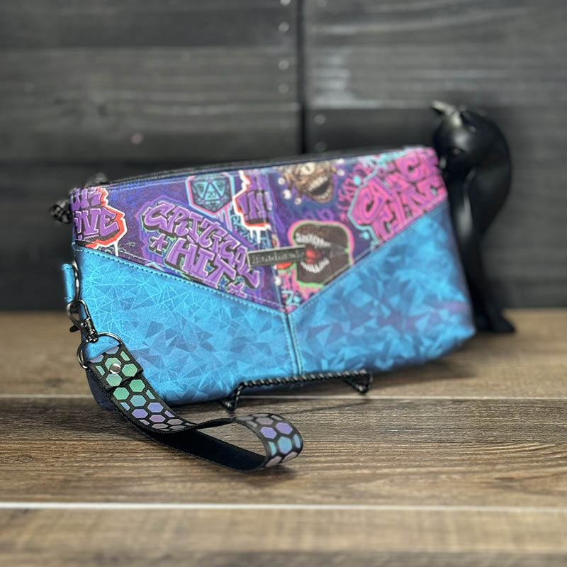 handmade wristlet featuring a graffiti design with mimic chests, beholders, and phrases like critical hit and roll for initiative