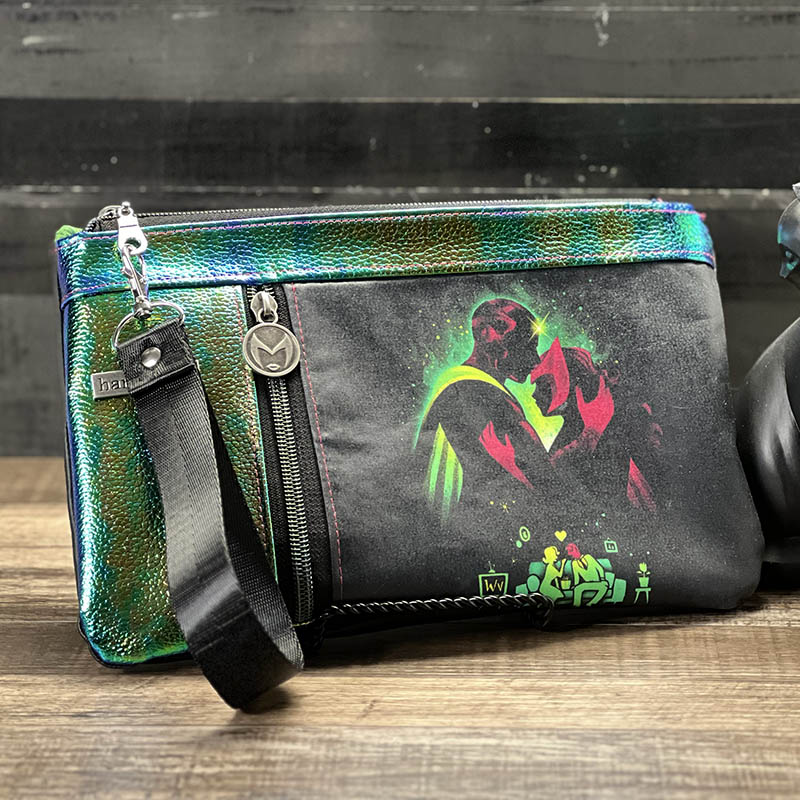 handmade zippy cluch with a fabric panel with a glowing silhouette design of a man and a woman embracing, trimmed in metallic green colorshift vinyl