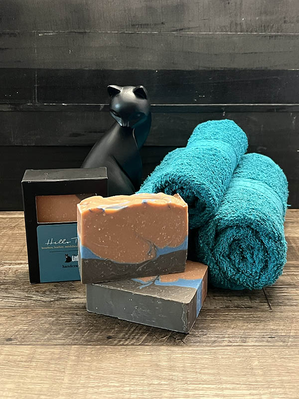 soap bars in brown and blue arranged with teal towls and a black cat statuette